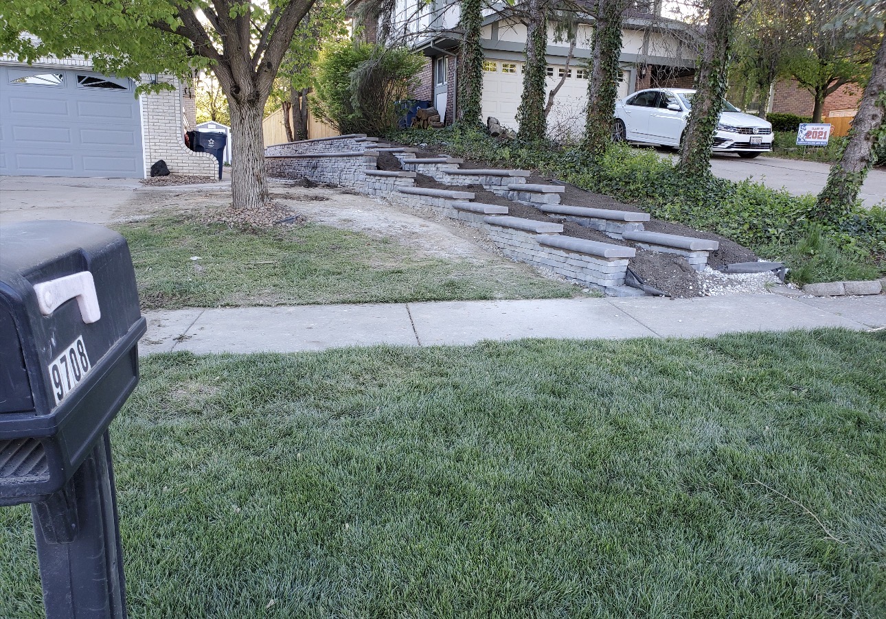Stone retaining wall with wide stone steps leading up a front yard slope