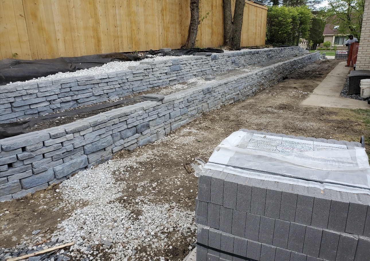 Double-tier stone wall with white decorative gravel and drainage fabric installed