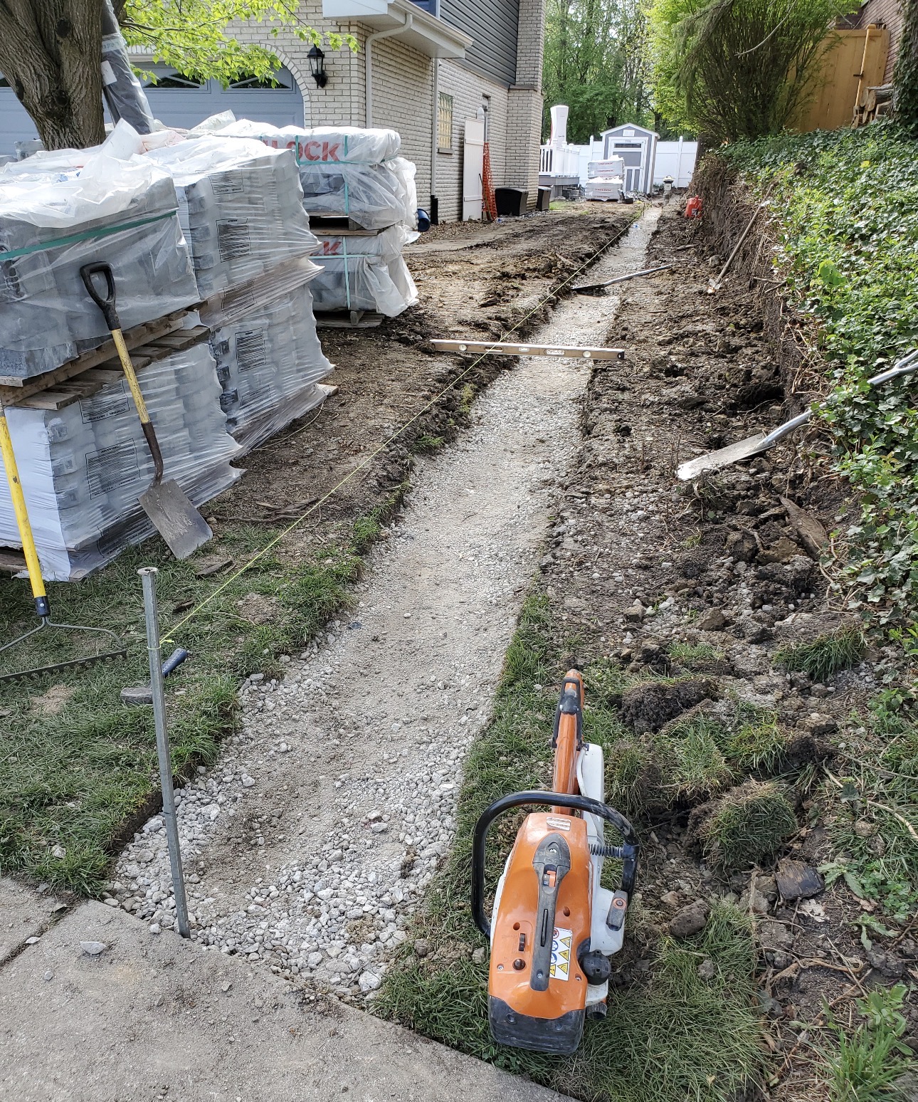 Excavated and compacted gravel base trench with string line for a new walkway