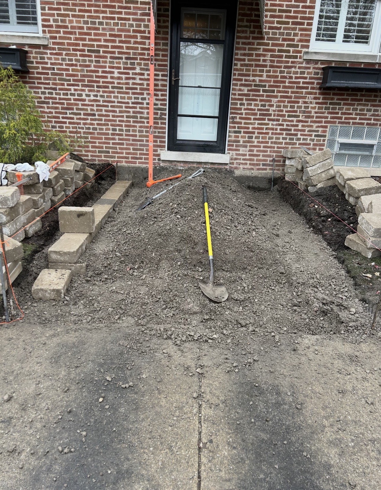 Excavated front entry with graded soil, string lines and stacked block