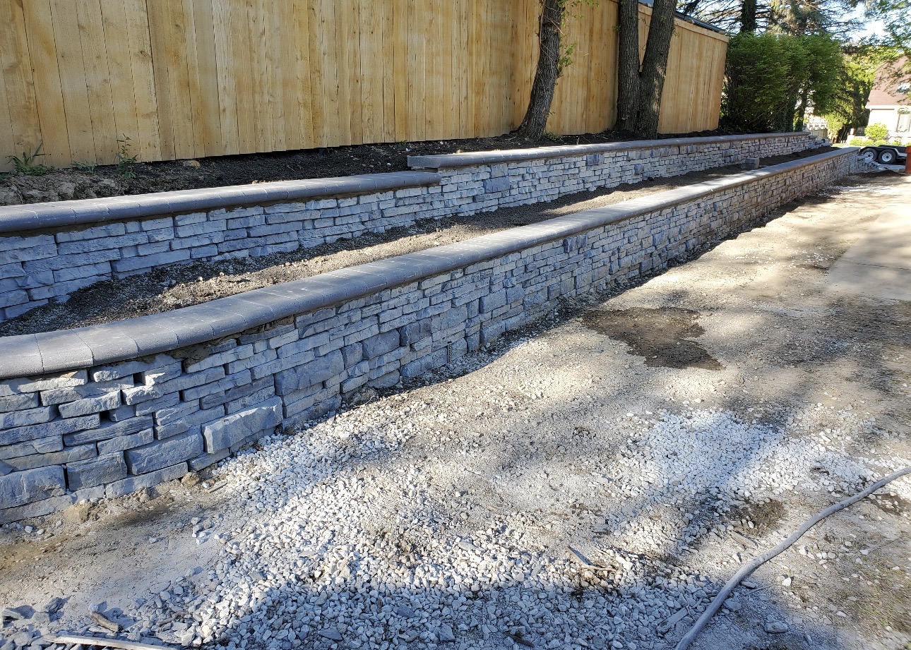 Terraced stone retaining walls with capped coping and planting beds between tiers