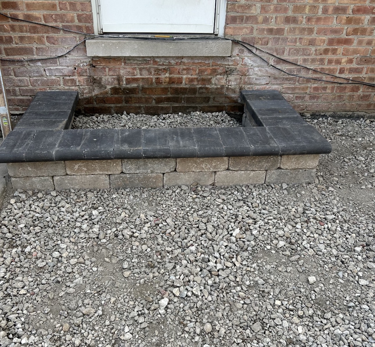 Rough block step base set on compacted gravel at a brick rear entry